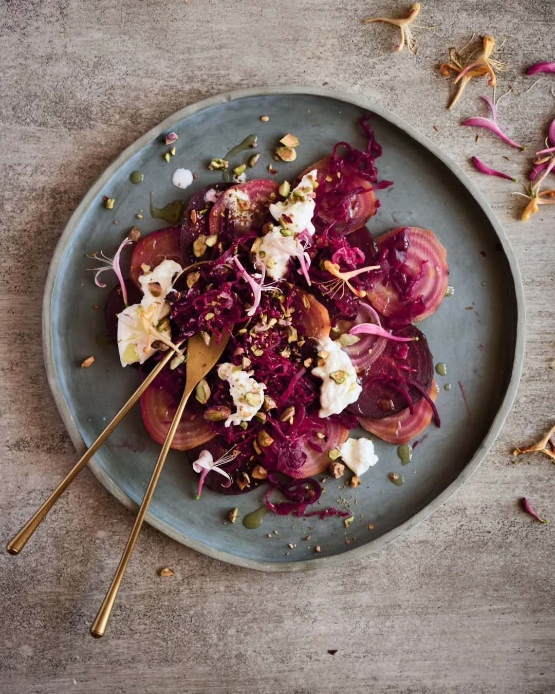 overhead macro image of beet salad with burrata and pistachio texture in bright scene