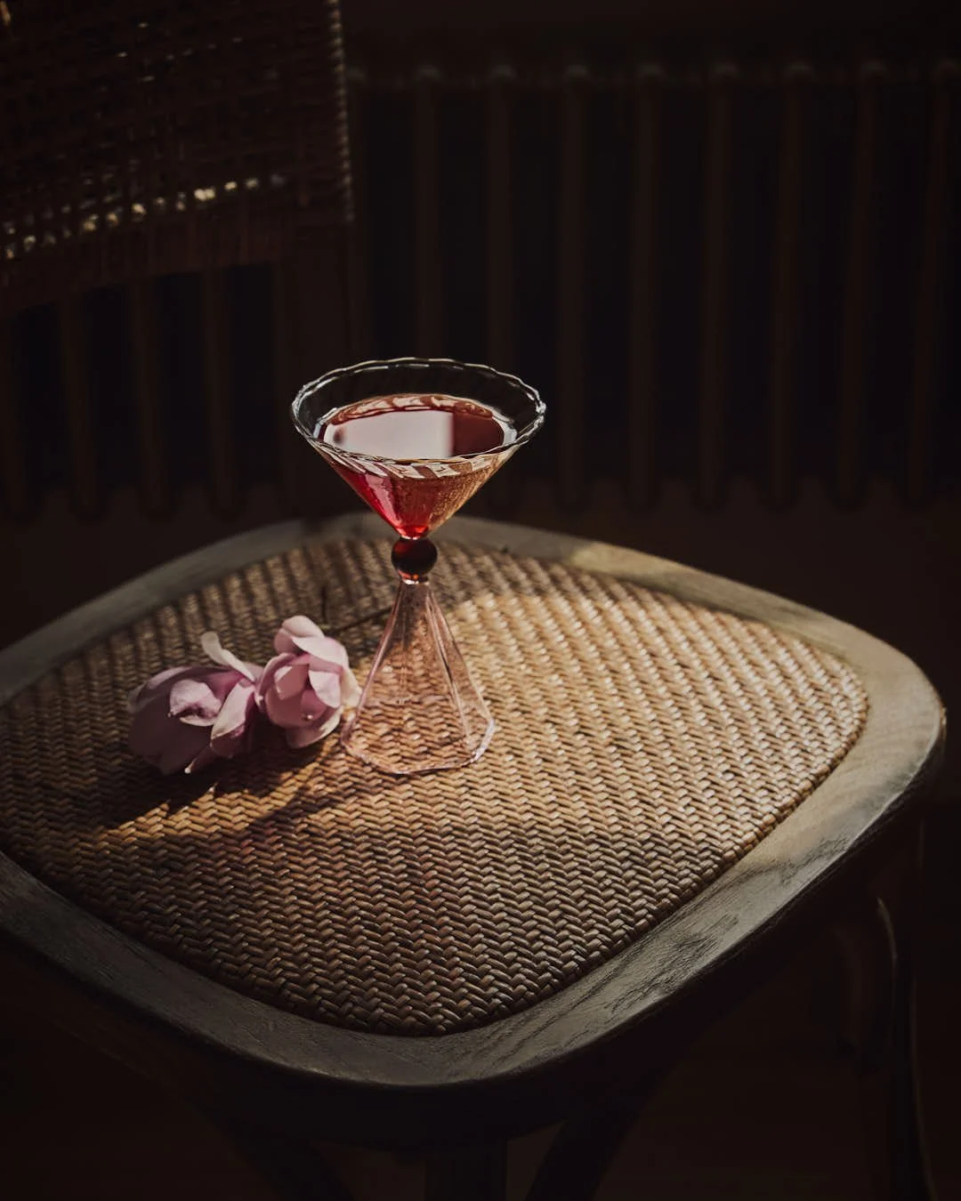 martini with red hue on chair next to magnolia flowers in stunning moody image