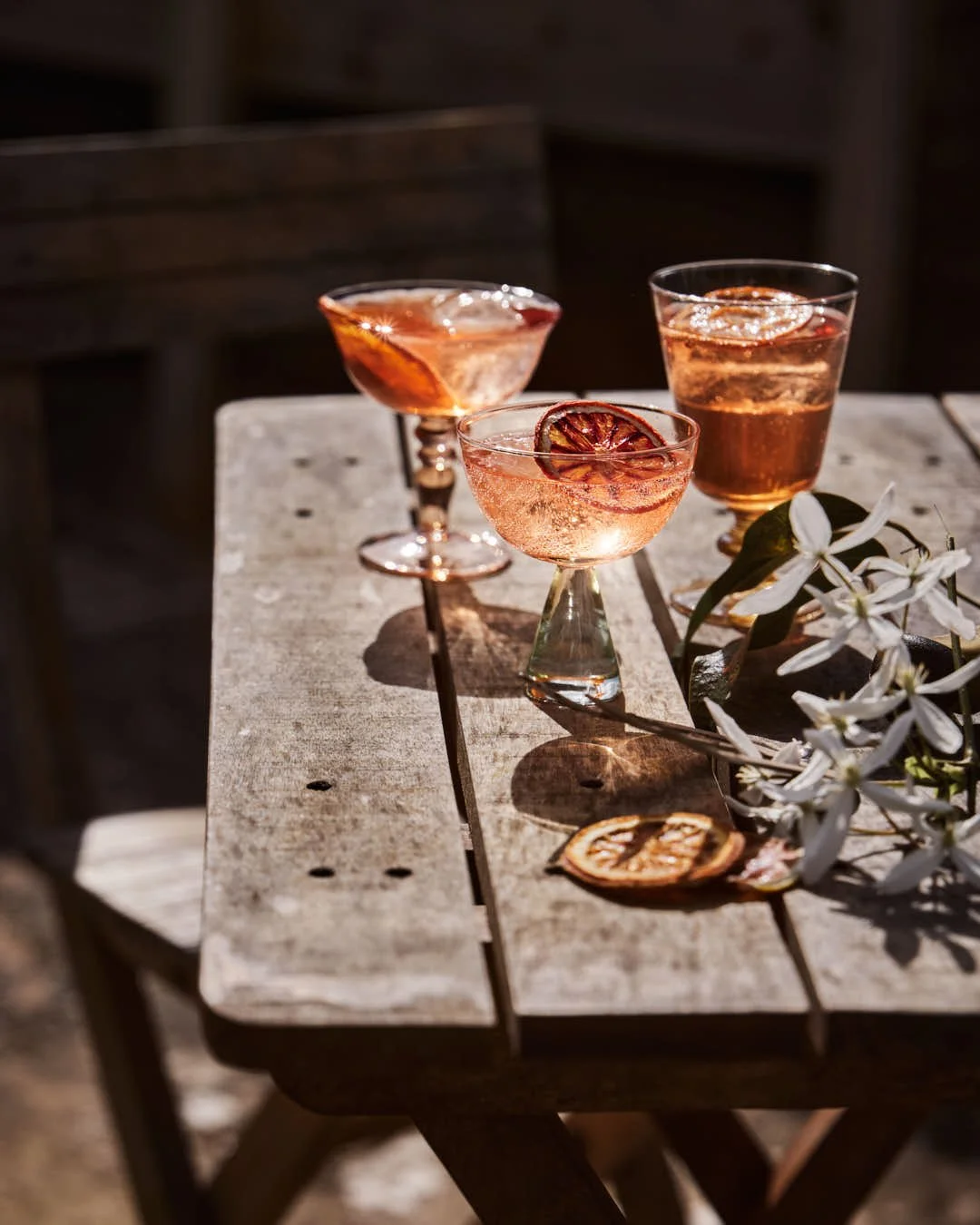 set of three glasses of spritz in outdoor sunny table scene with rustic wood
