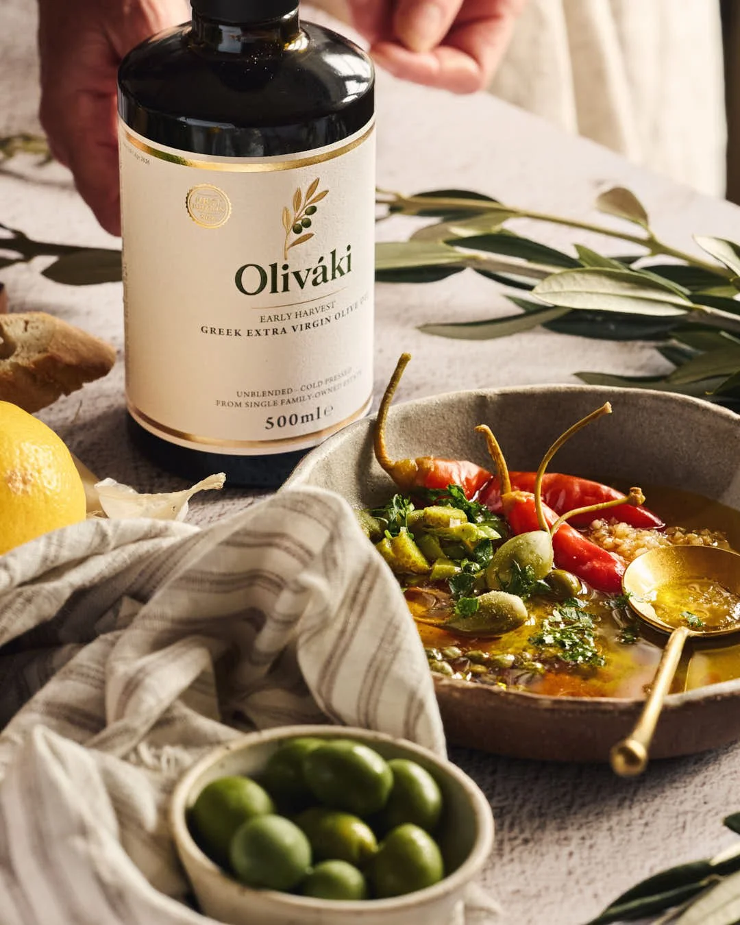 angled image of olive oil dipping bowl with herbs and bottle of olive oil