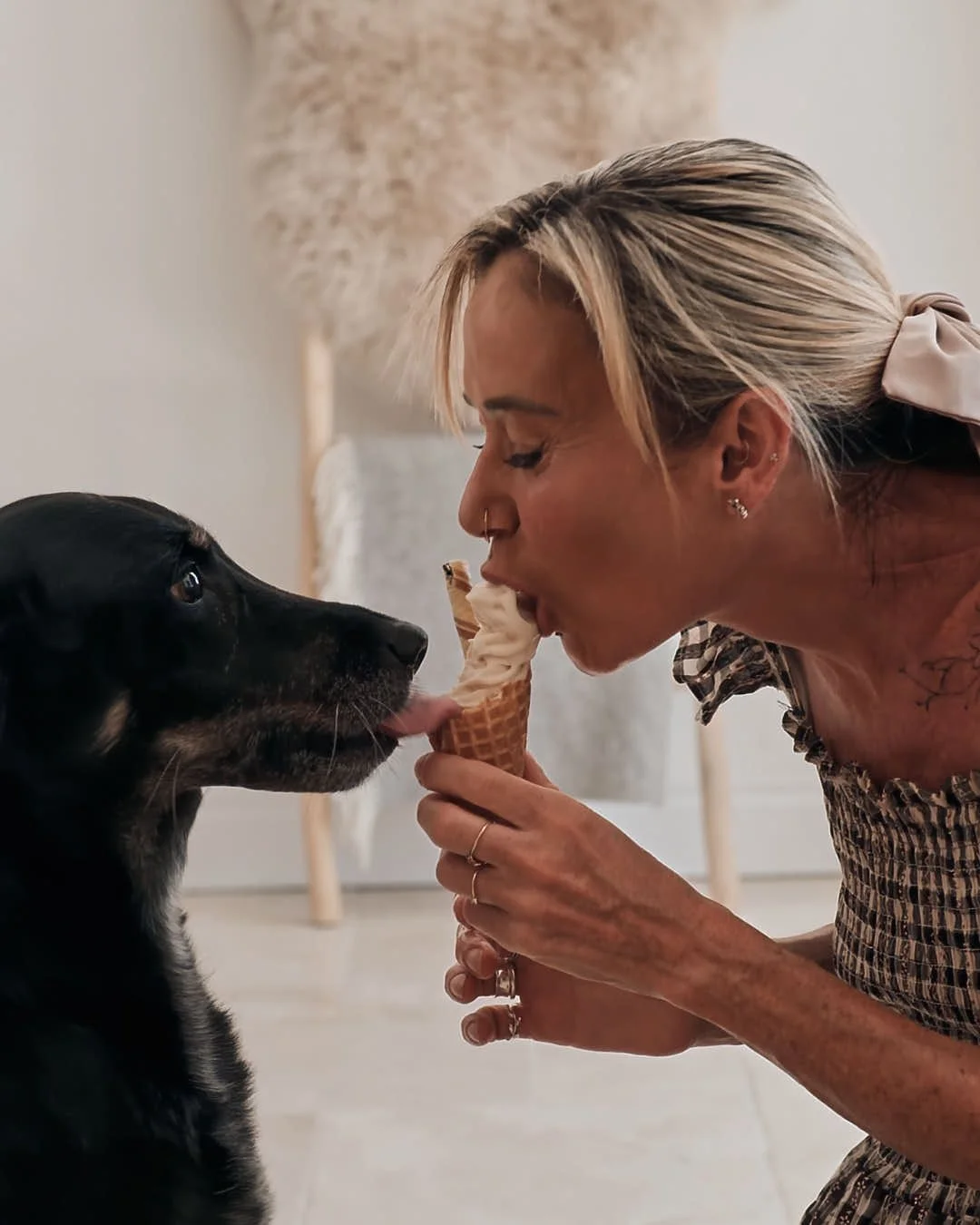 girl and dog sharing ice cream in neutral toned warm lit room