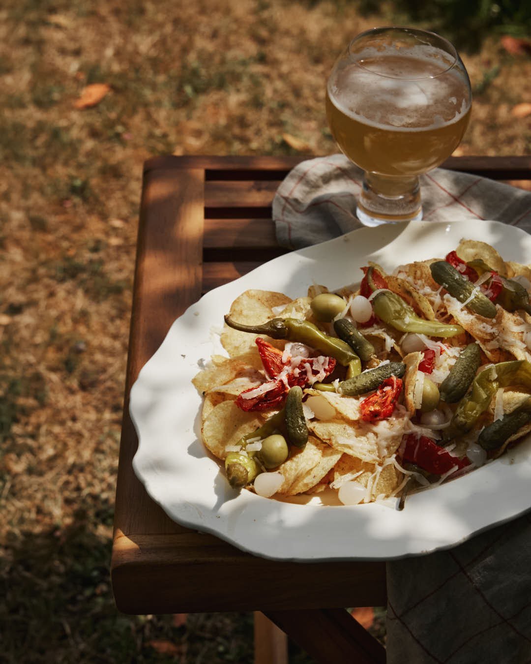 image of cream vintage platter with crisps topped with array of charcuterie with pickles and cheese