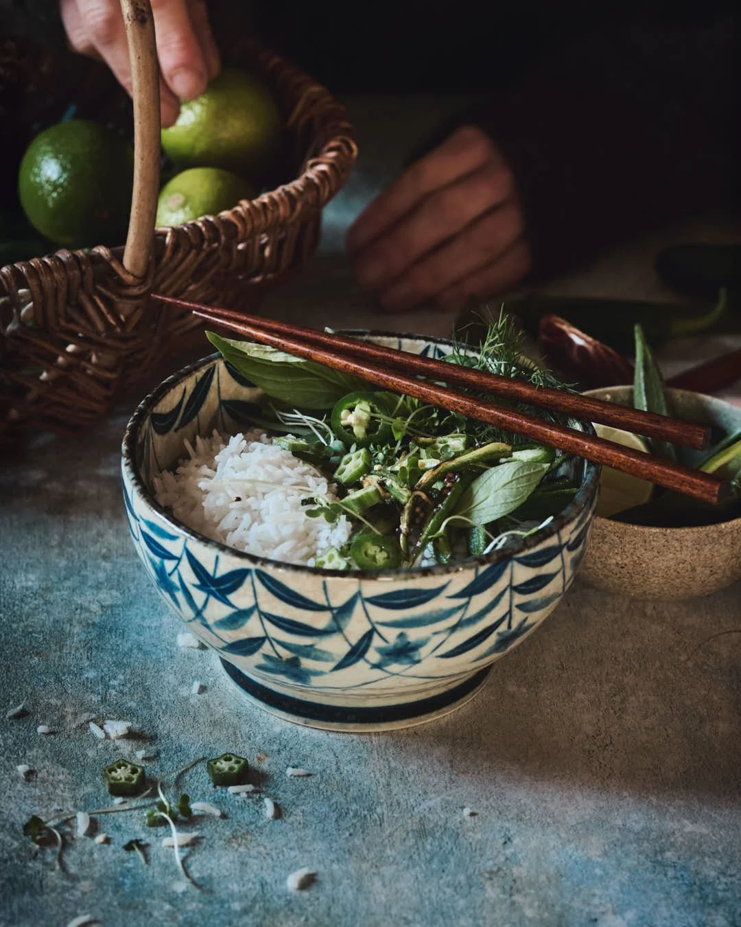 angled image of mottled blue backdrop with a asian inspired bowl of rice and okra with chillis