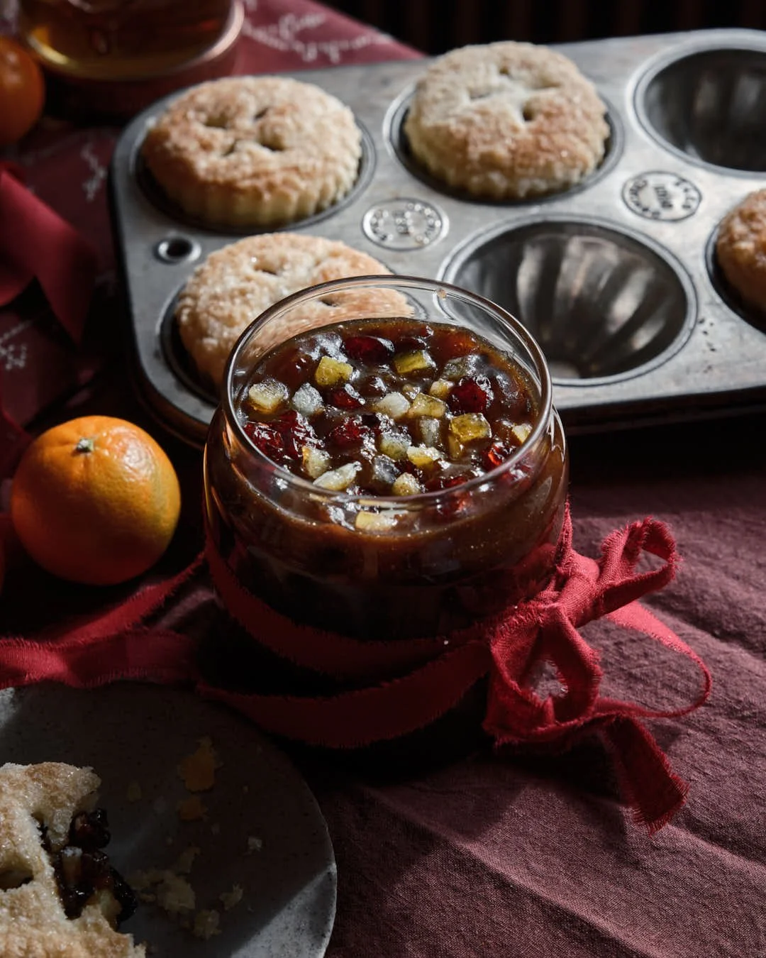 macro image of jar of mincemeat in backlight with mince pies to back
