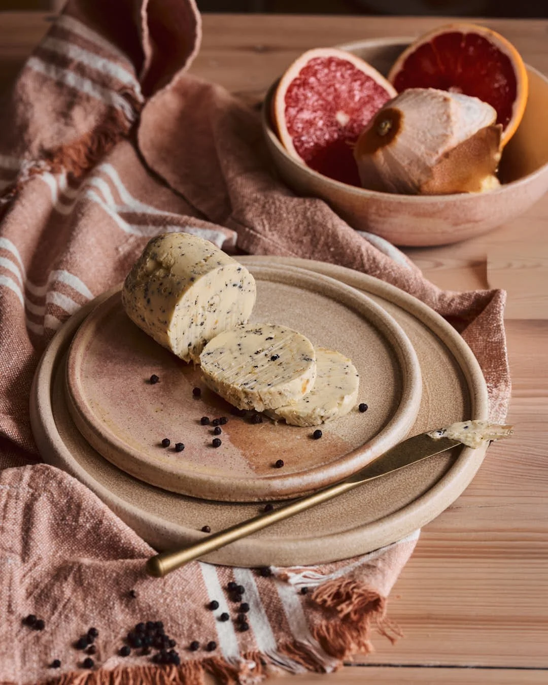 straight on image of compound butter on plate with two slices to show peppercorn flecks