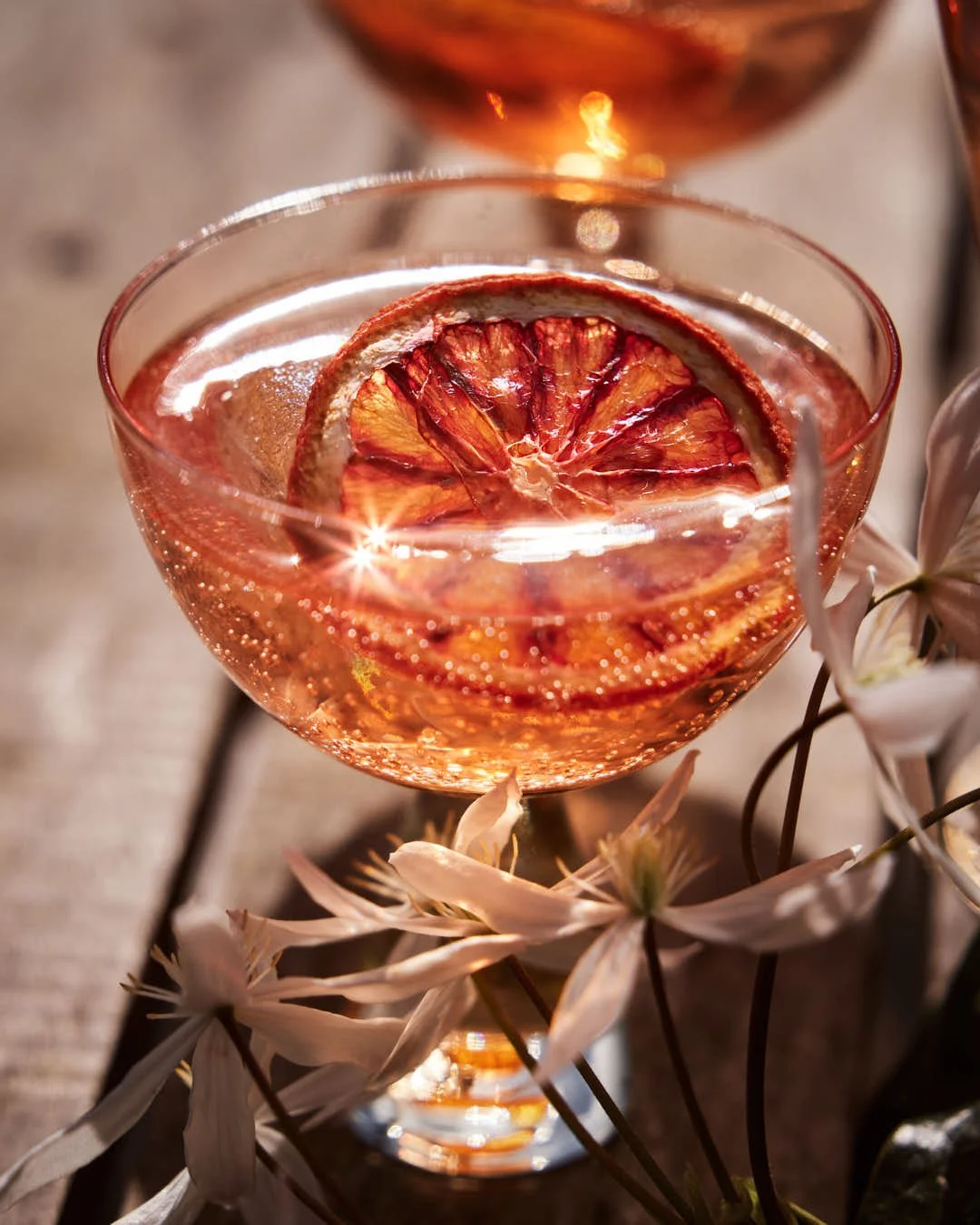 macro image of orange hued spritz in glass in outdoor sunlit scene