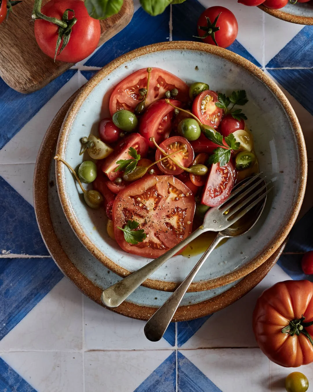 flatlay image of tomato salad on blue and white tiled surface