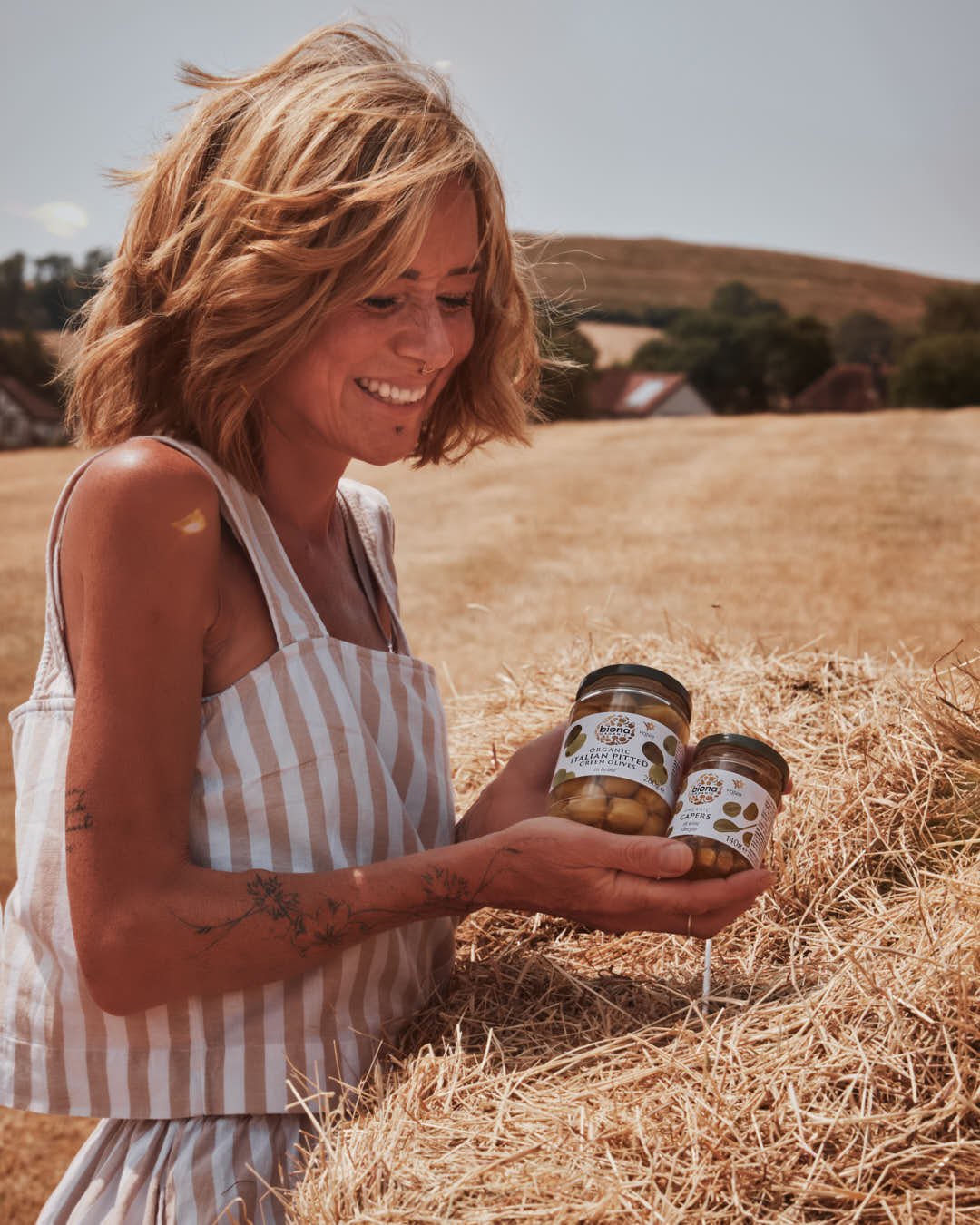 girl with two jars of antipasti by hay bales in summer shoot