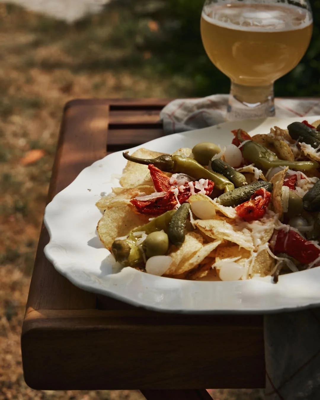 macro image of image of cream vintage platter with crisps topped with array of charcuterie with pickles and cheese