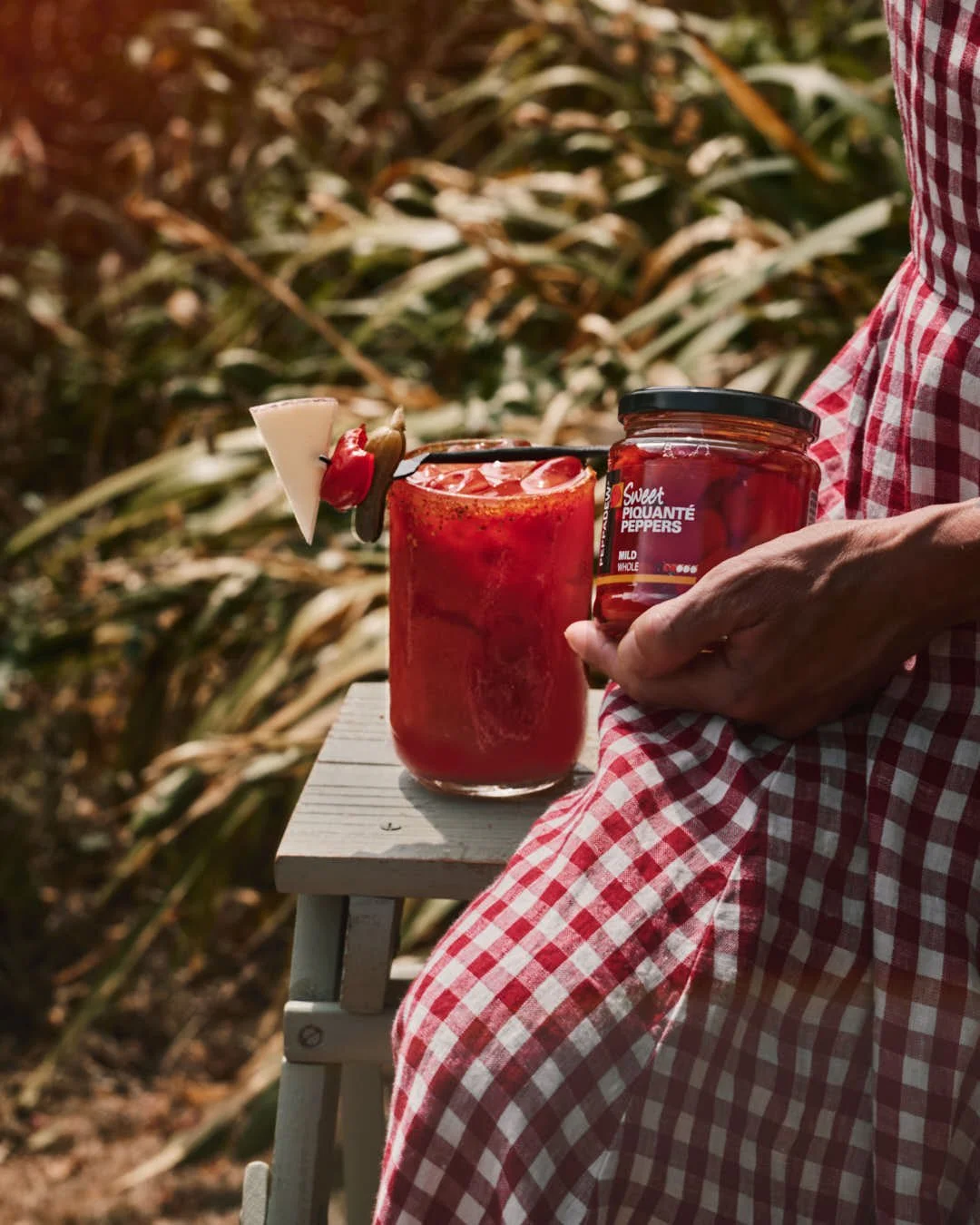 girl in gingham dress with tomato drink in summer shoot