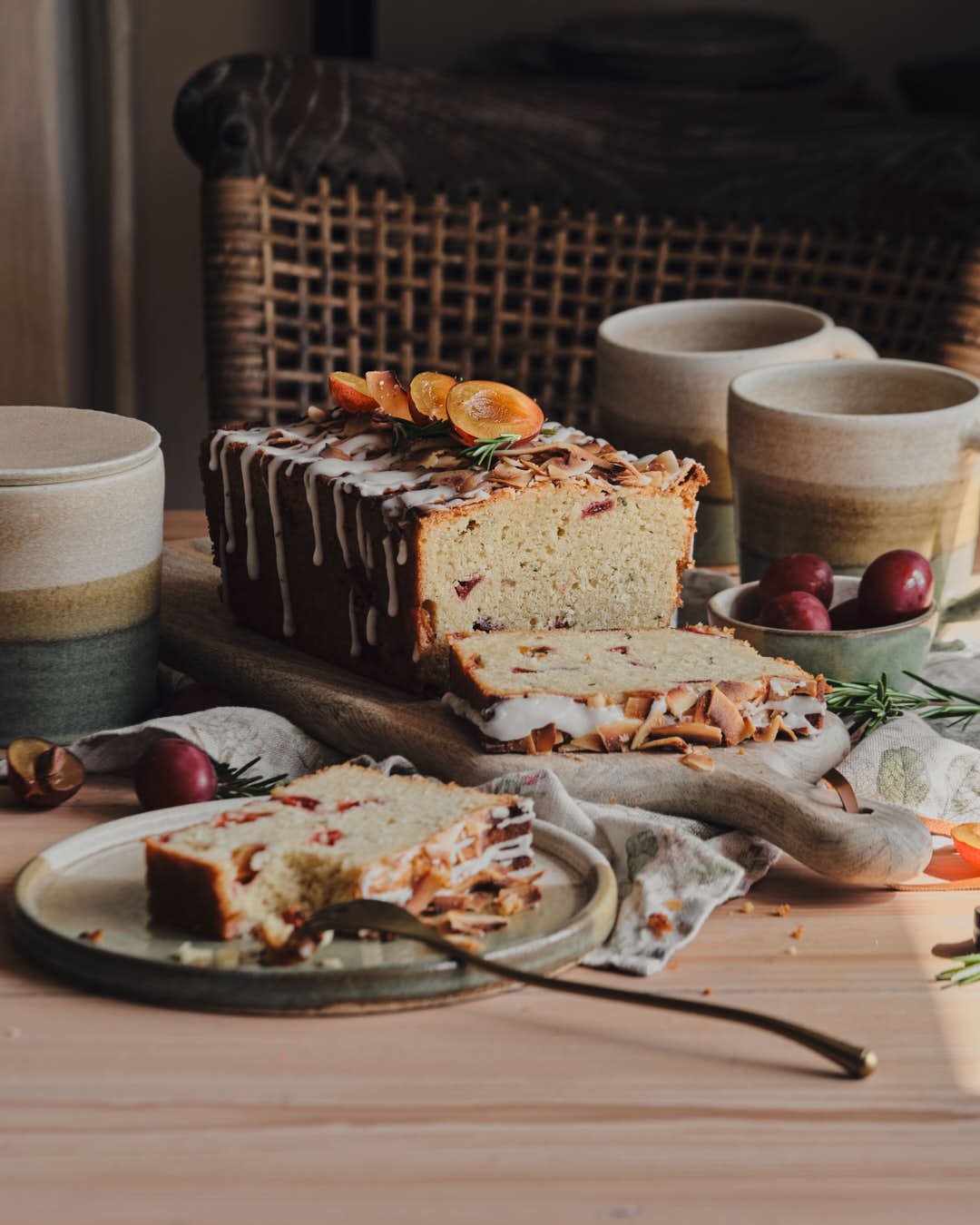 straight on image of loaf cake in rustic farmhhouse setting with plum and rosemary garnish