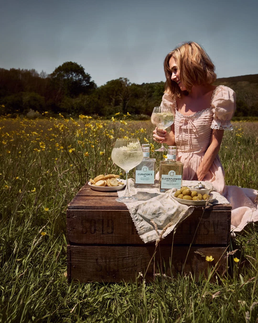girl enjoying spritz in wildflower meadow in summer sunshine