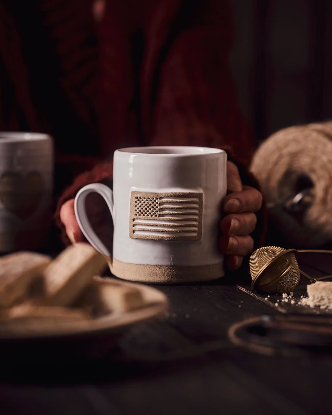 macro image of girls hands in sweater holding mug in cosy moody scene