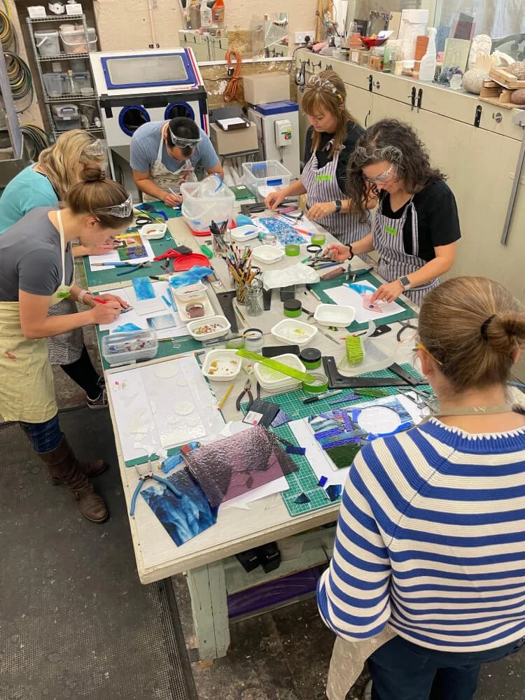 The picture is taken above the central work table. People are busy making their own glass dishes and landscapes.