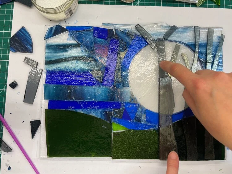 Ali has placed her finger onto the winter night scene. A large white moon has a grey trees laid in front of it.