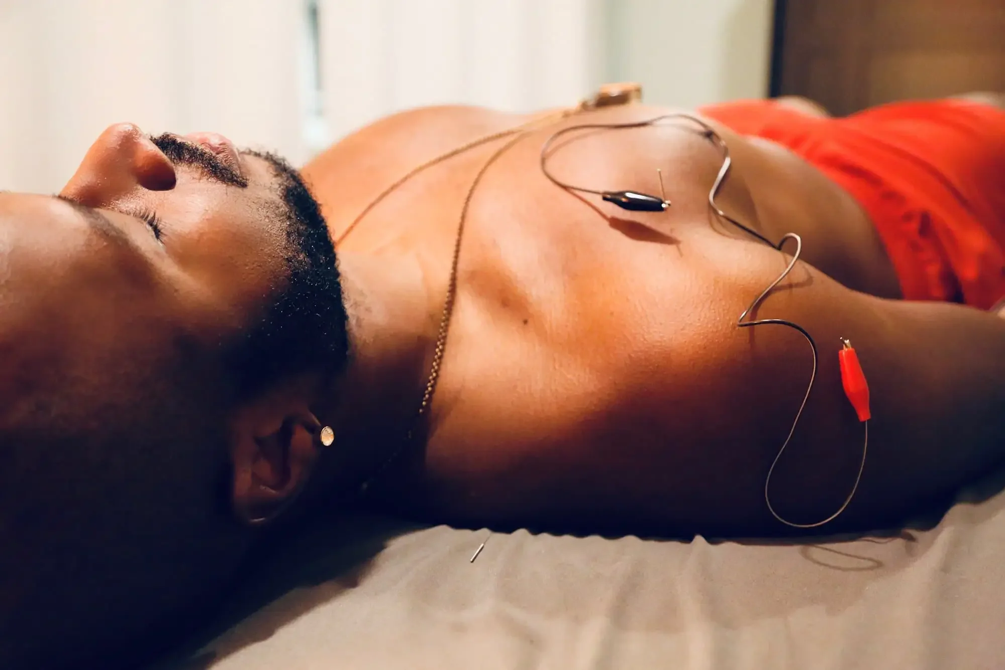 A man is lying down with electrocardiogram electrodes attached to his chest.