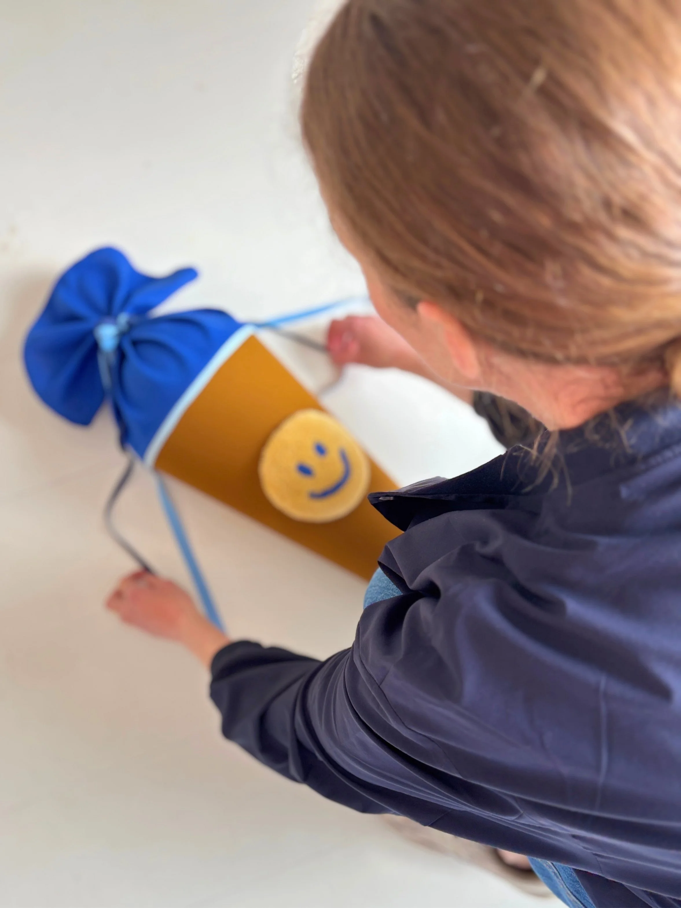 Schultüte mit Tufting Motiv in Form eines Smileys wird von einer Frau liebevoll zurechtgelegt