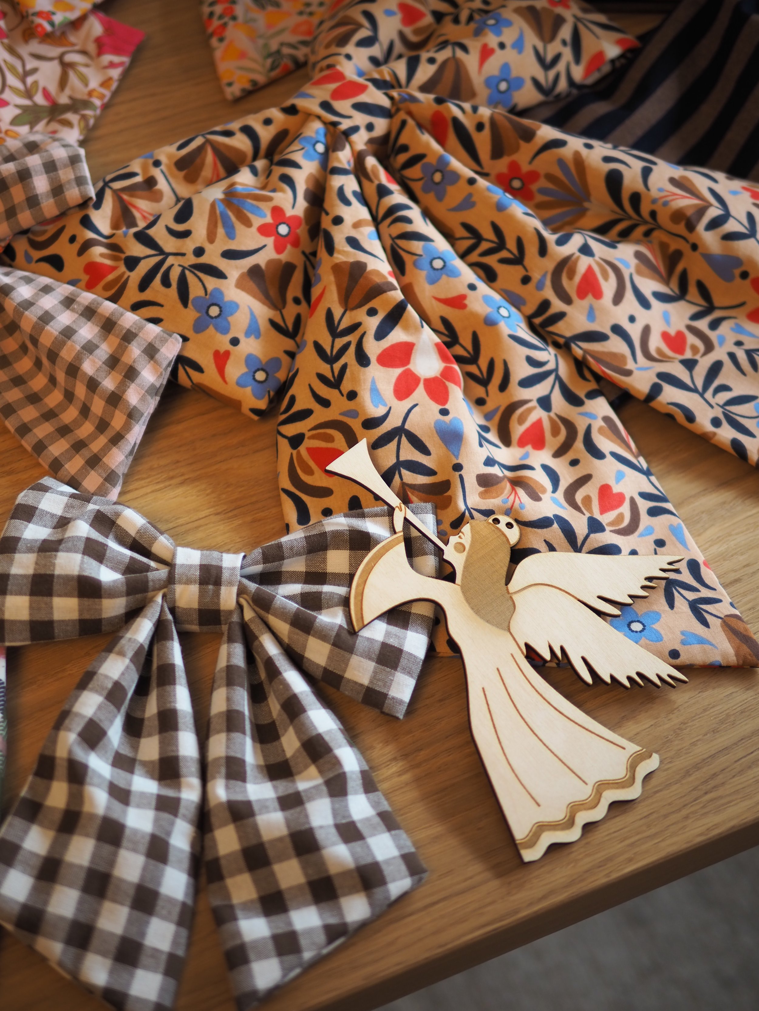 Handgefertigte Stoffschleifen in verschiedenen weihnachtlichen Dessins mit einem filigranen Engel aus Holz