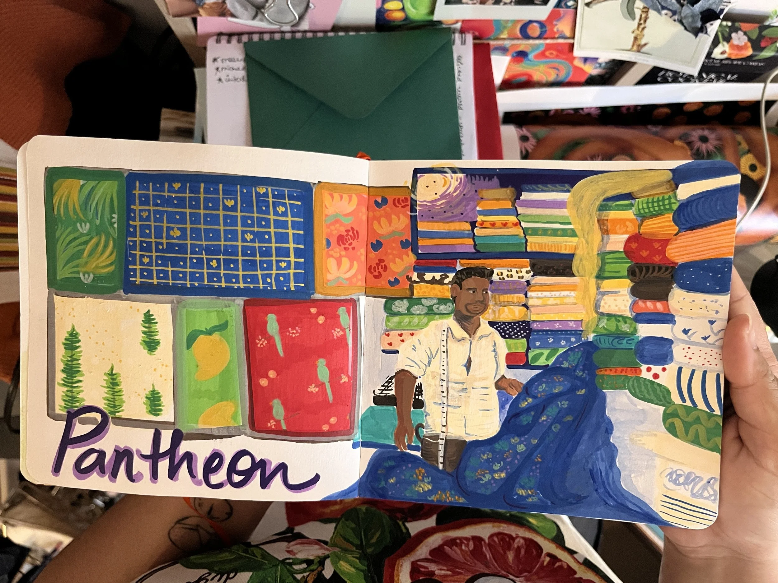 Sketchbook page with acrylic markers and watercolour showing a shop at Pantheon Road cloth market in Chennai