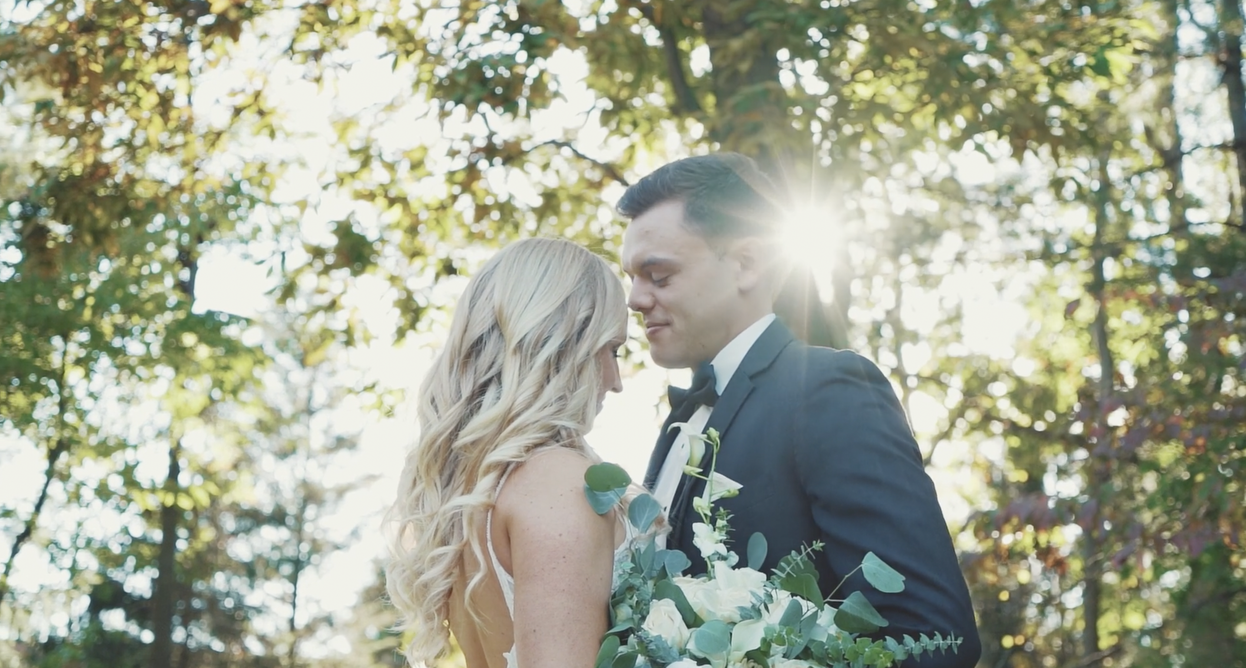 A New Jersey based bride and groom sharing an intimate moment outdoors with the sun shining through trees in the background. NJ Wedding videography at the Pleasantdale Chateau by TruLove Films