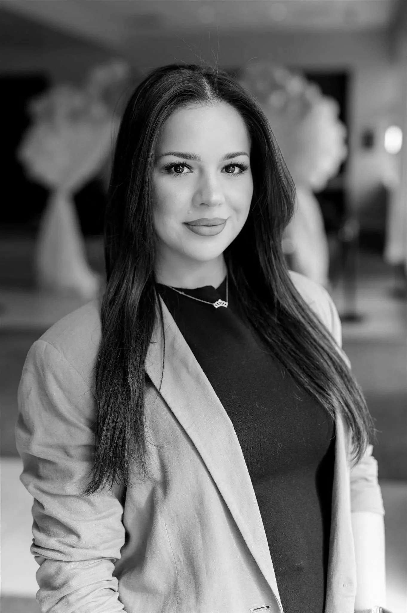 Black and white portrait of a woman with long hair wearing a dark blazer and top.