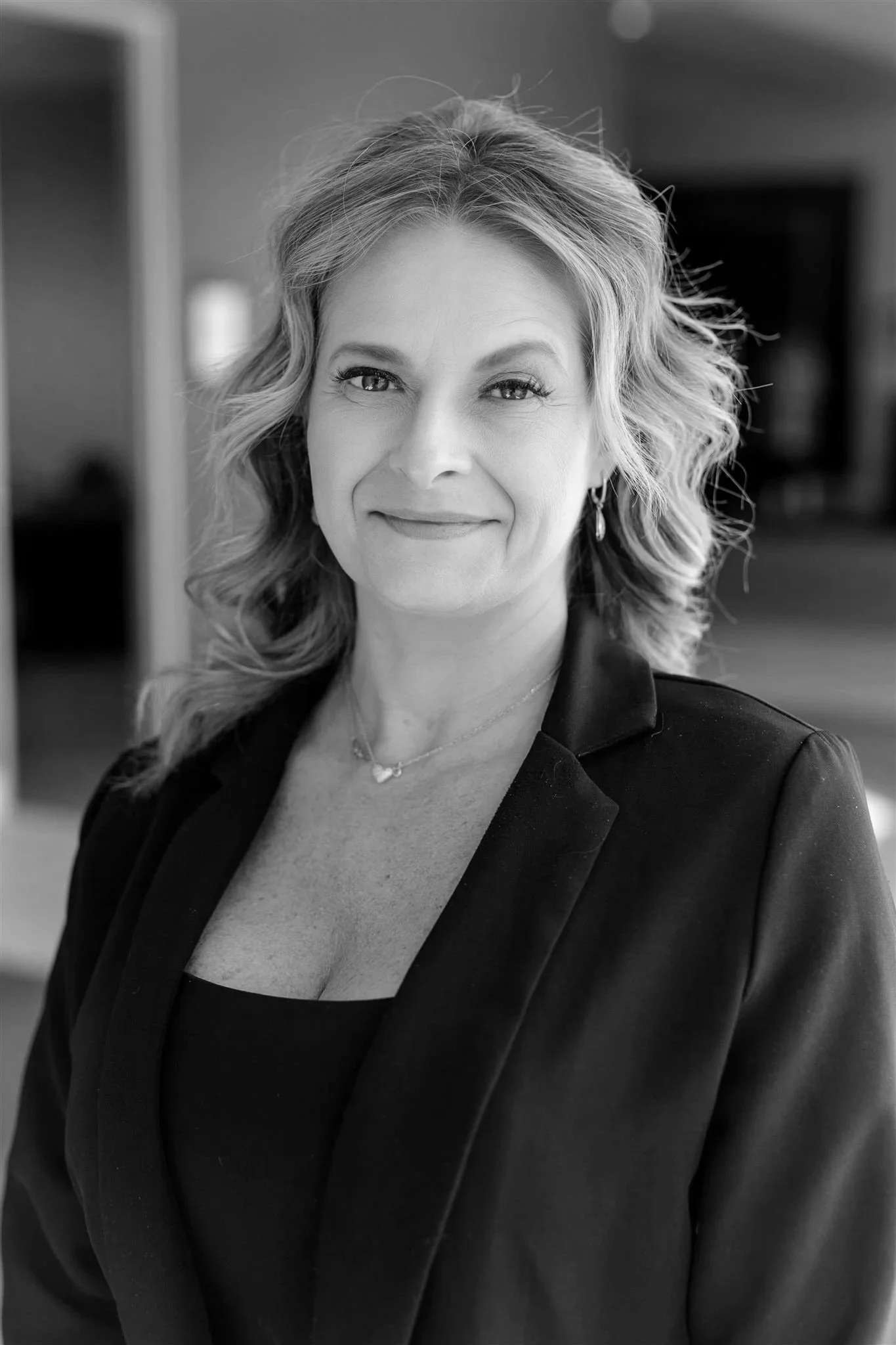 Black and white photo of a smiling woman with shoulder-length hair wearing a button-up shirt.