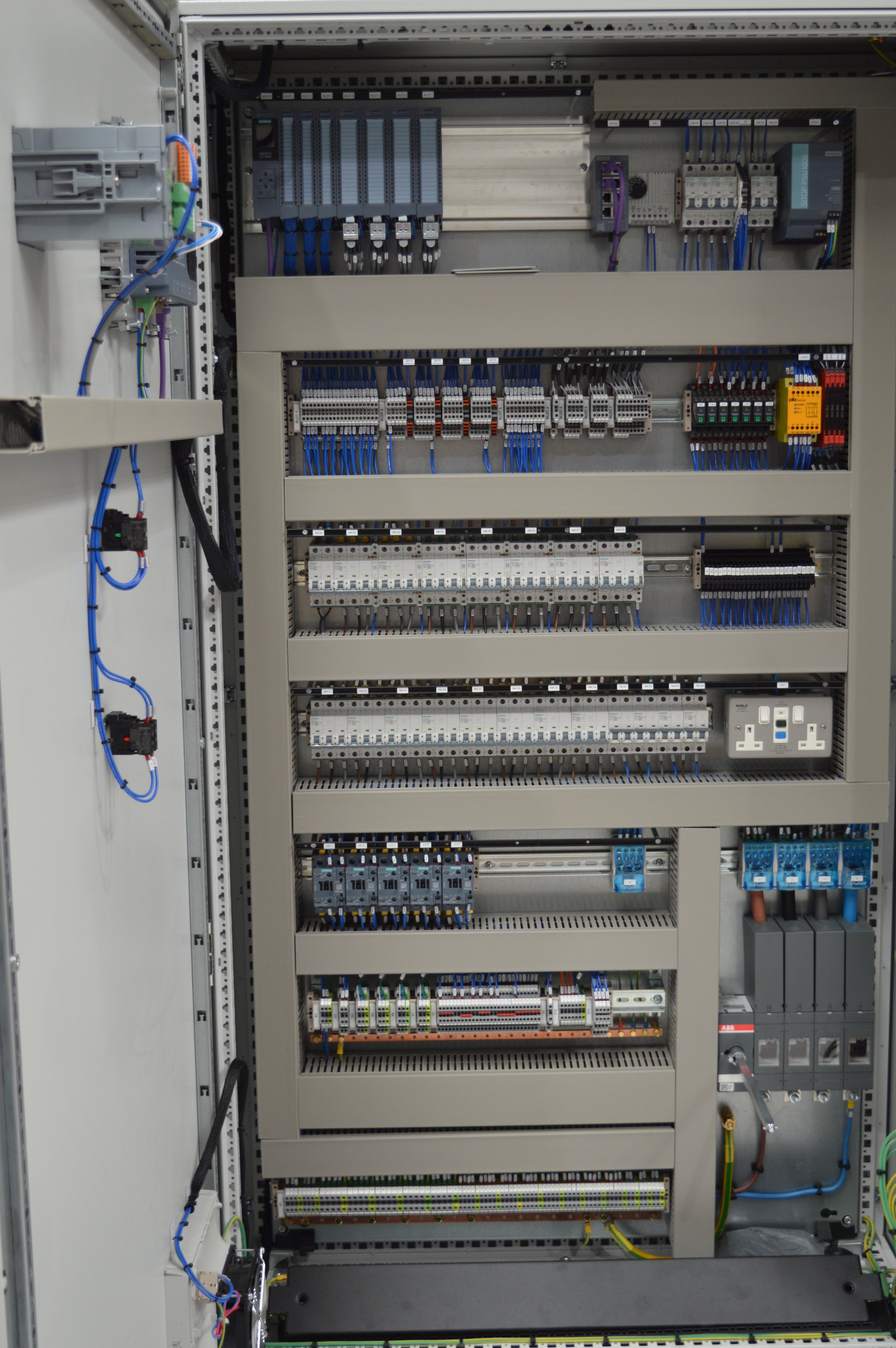 Electrical control panel with various switches, circuit breakers, terminals, and wiring components.