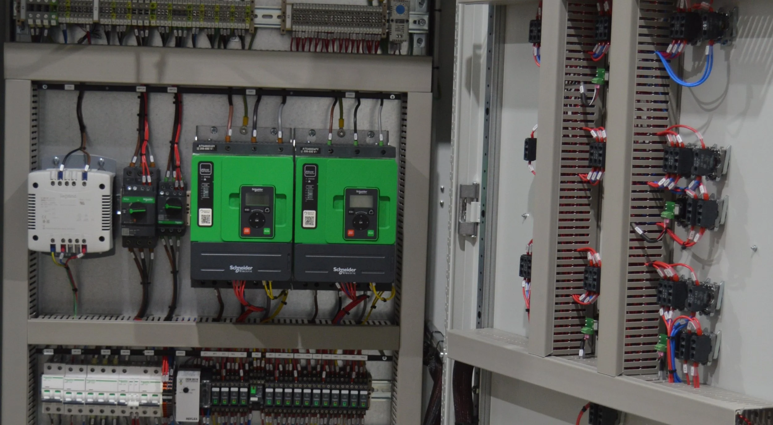 Electrical control panel with multiple circuit breakers and red wires connected.