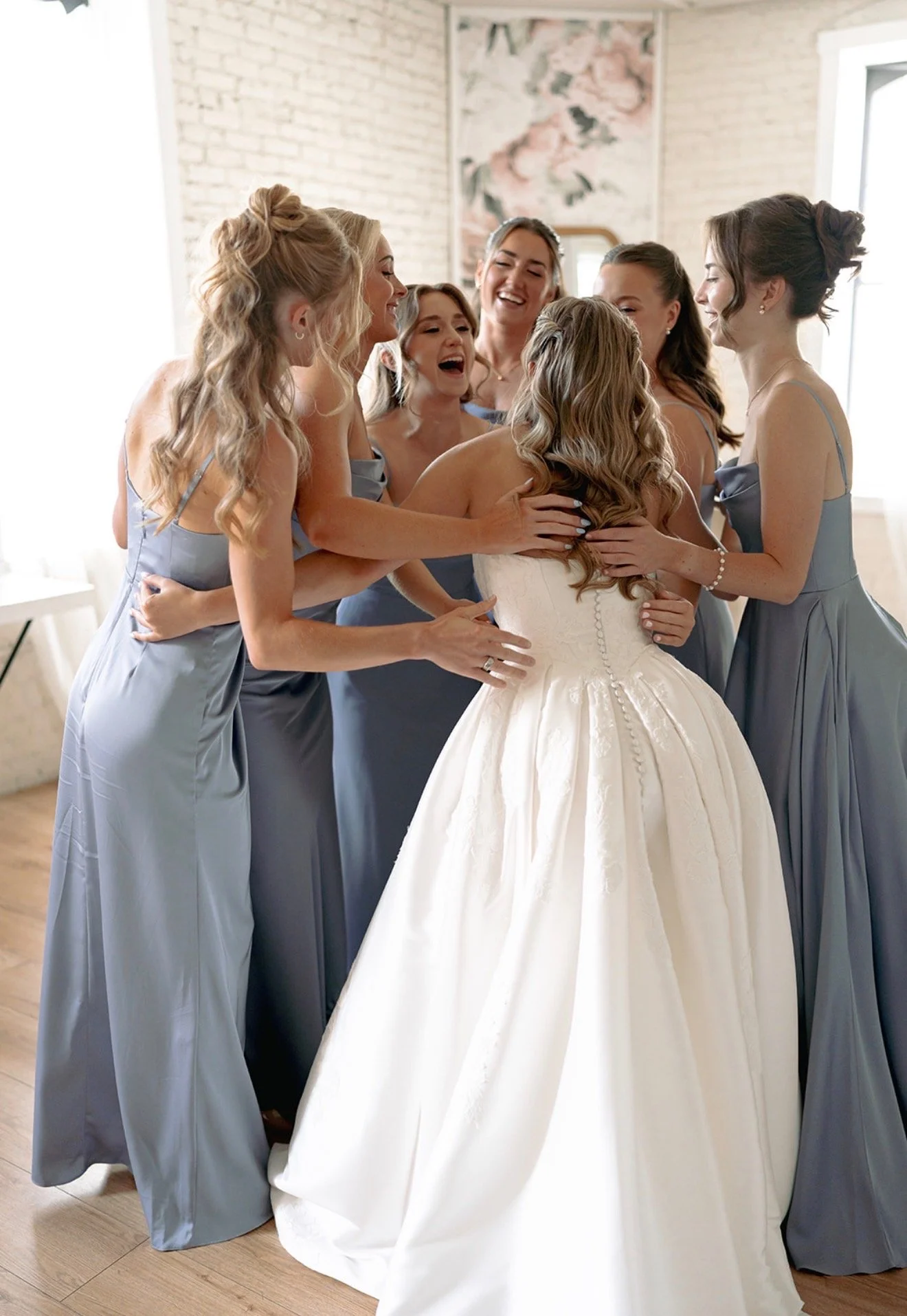 Bridesmaid celebrating with hugs for the bride after her first look with them