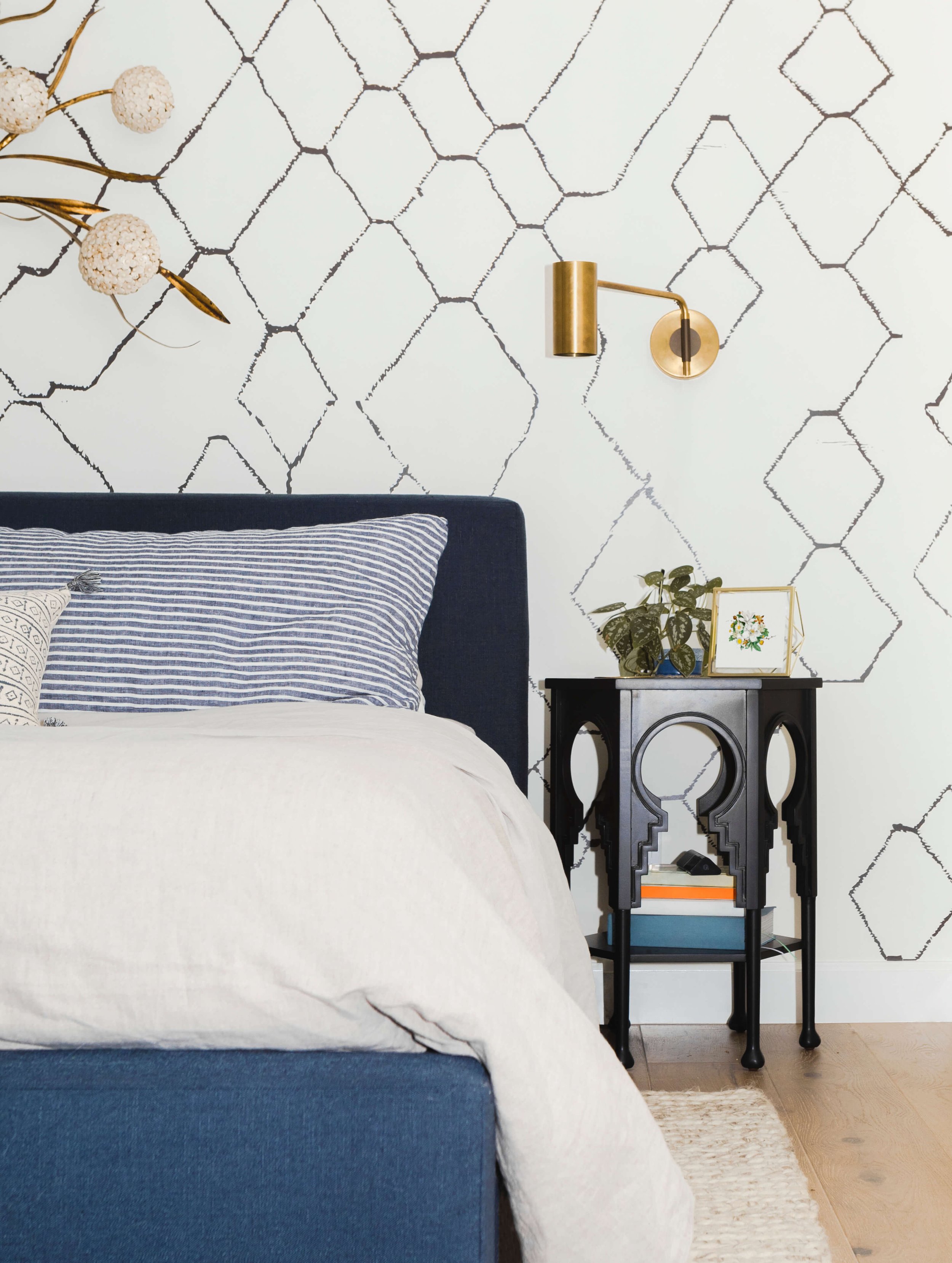 clean modern bedroom with wallpaper and gold wall sconce