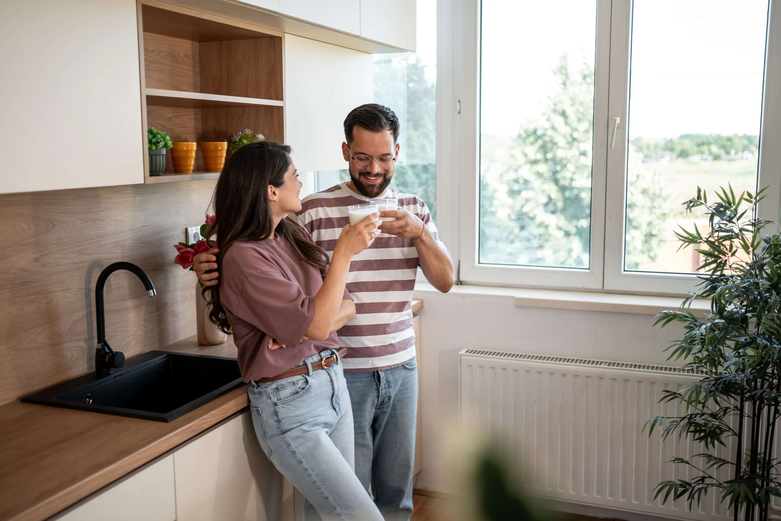 Happy couple toasting with milk in modern kitchen