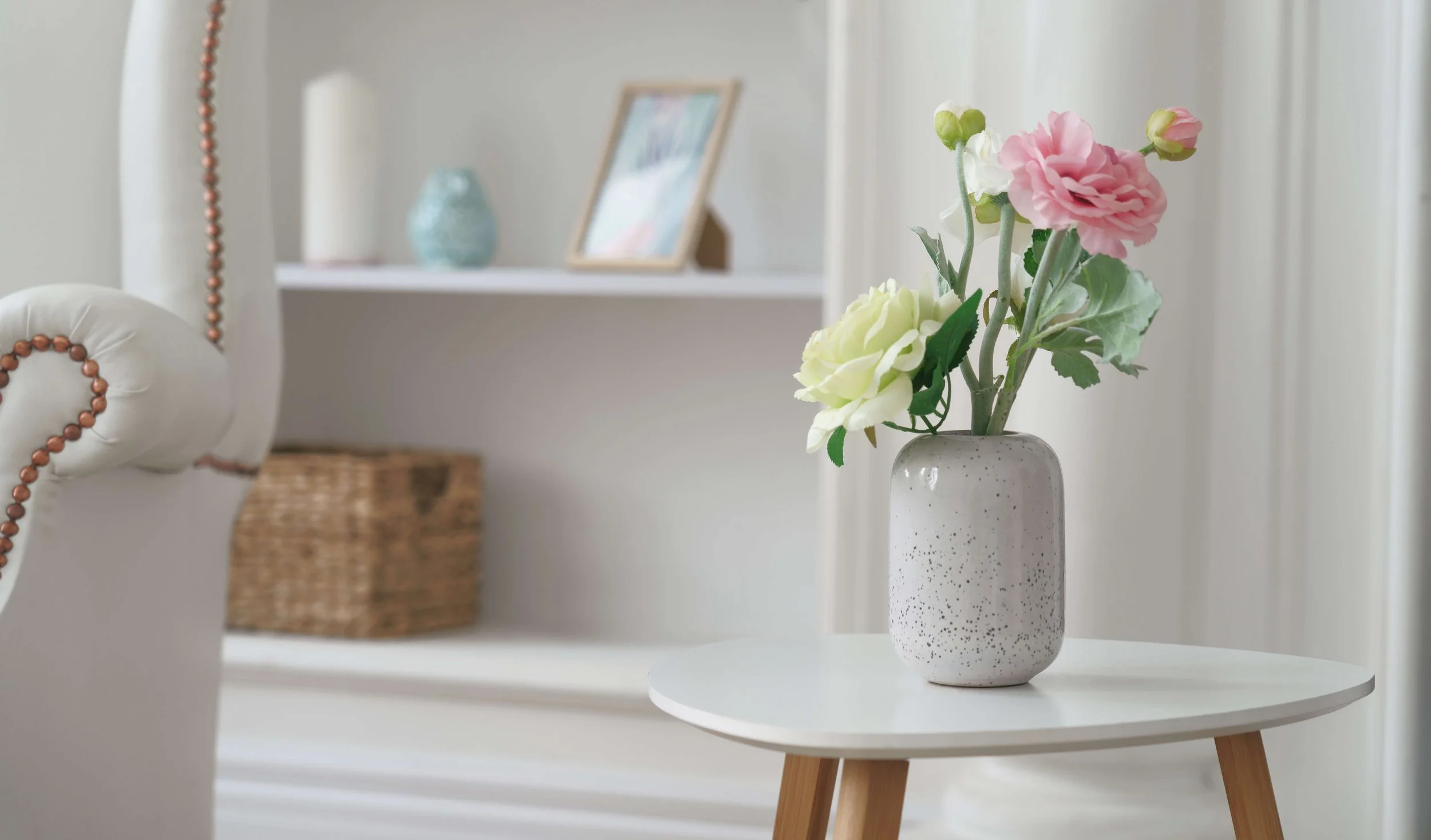 Pink and yellow roses in modern white vase on white table