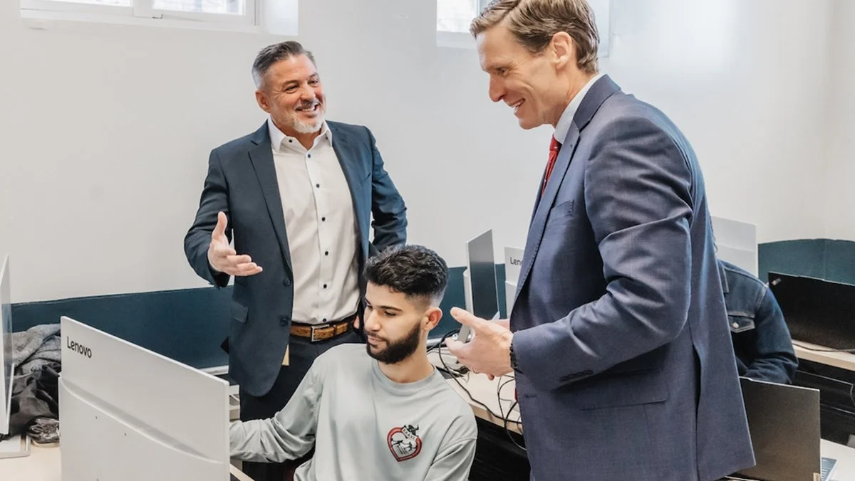 Three adults in a technology learning lab, gathered around a computer screen.