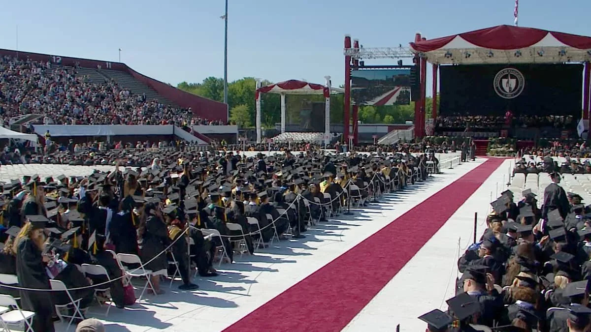 Students sitting at Commencement in front of stage with crowd