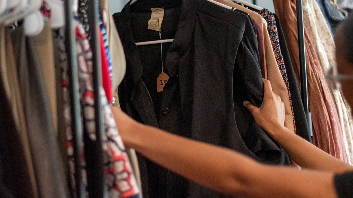 Hands shuffling through clothing on a rack.