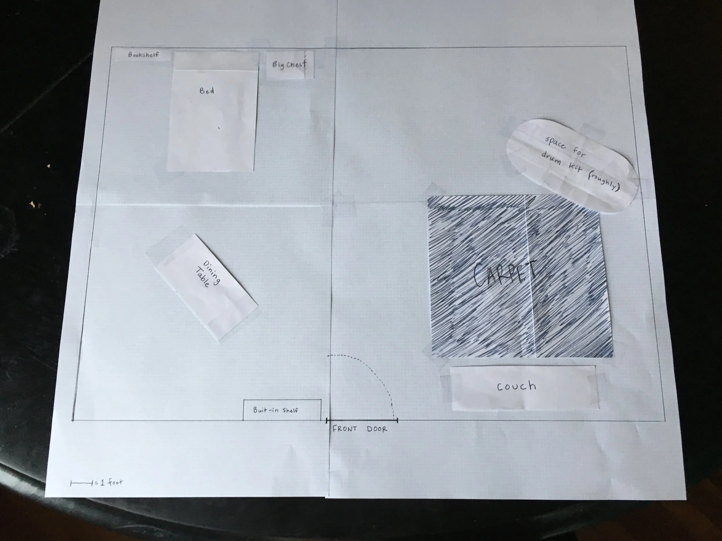 A hand drawn aerial floor plan uses scaled cut out pieces of paper to represent the furniture in the space.