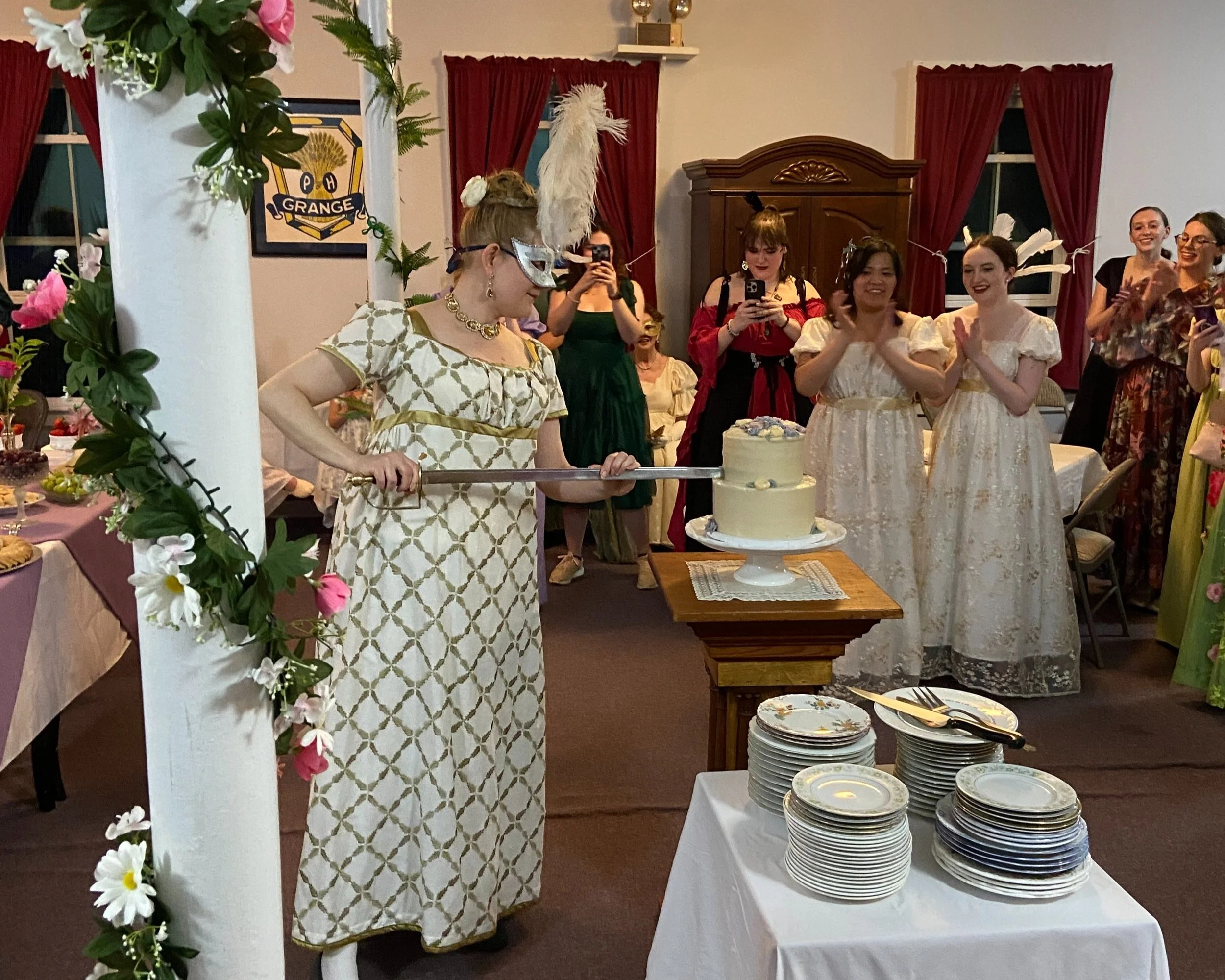 Catherine D. brandishes our cake sword to cut the lovely vegan and gluten-free cake at last year's may masquerade bridgerton ball