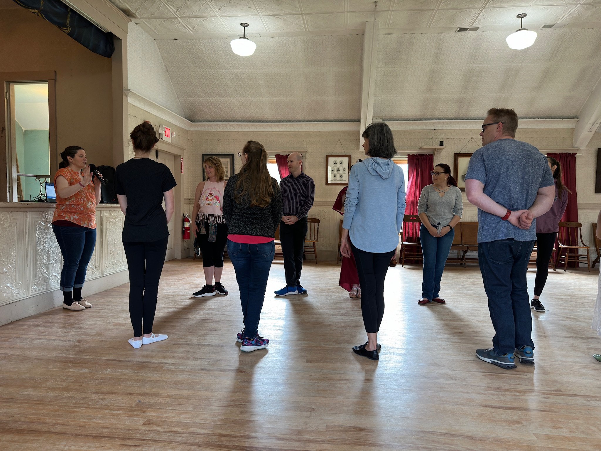 a member of footwork and frolick teaches beginner historical dances to a room of bridgerton ball workshop attendees