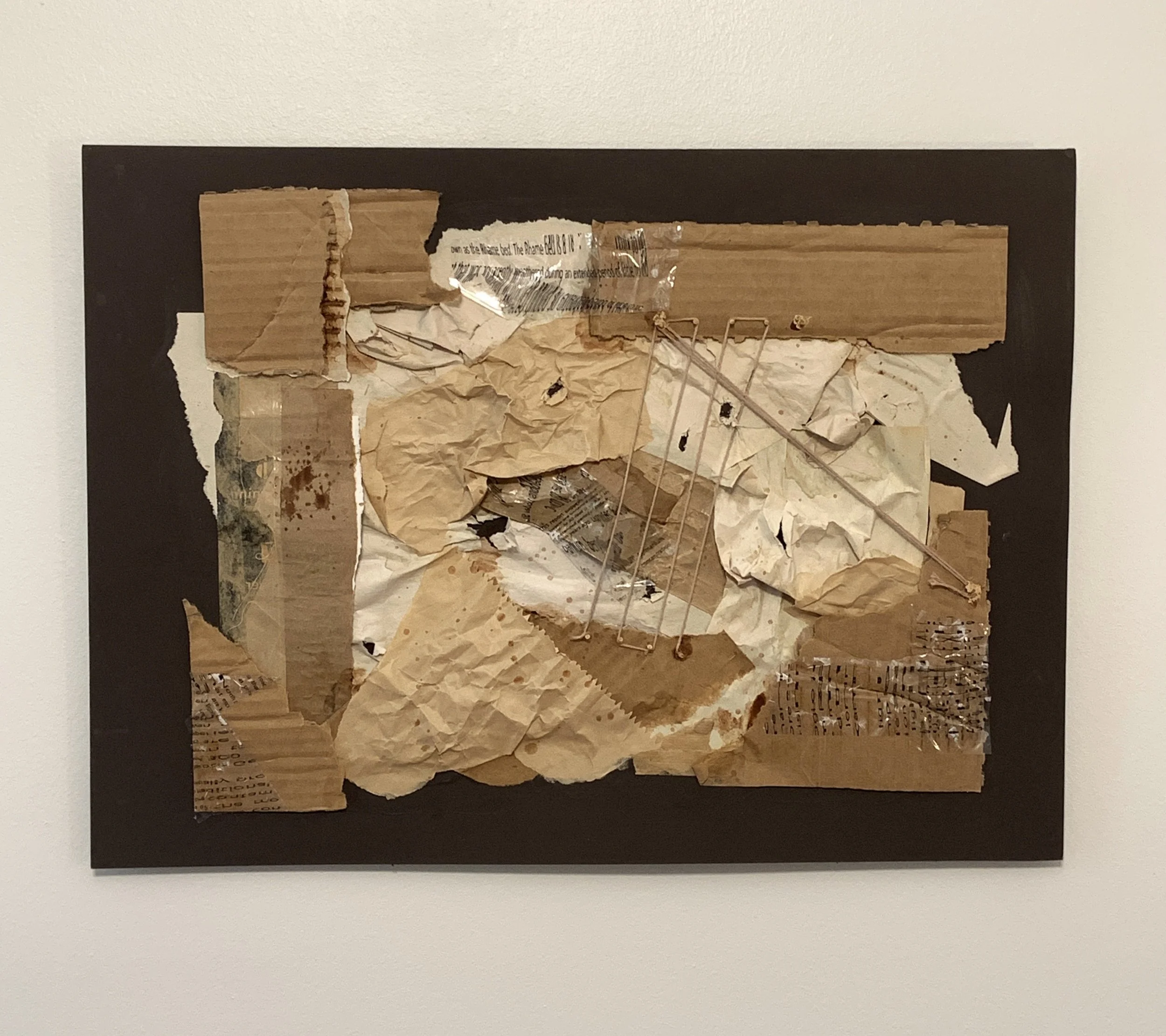 Mixed media artwork with torn paper, crumpled paper, and  cardboard pieces mounted on a dark brown backing
