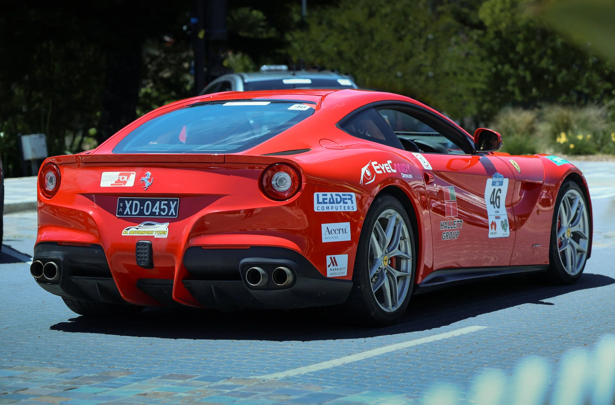 Red Ferrari sports car with racing stickers parked outdoors on a paved surface.