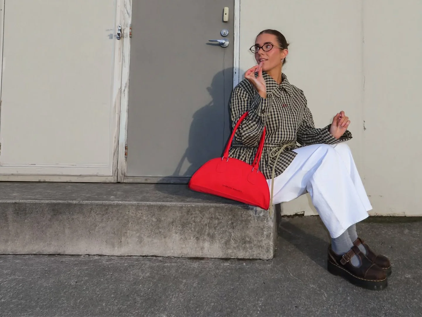 Molly Cochrane sitting on a concrete step with a red bag