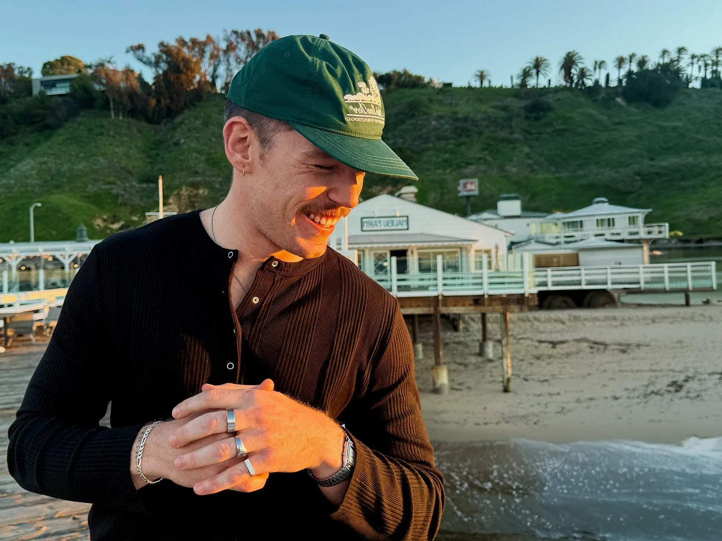 Kalum Murray at the beach for No Sad Cowboys in a green hat