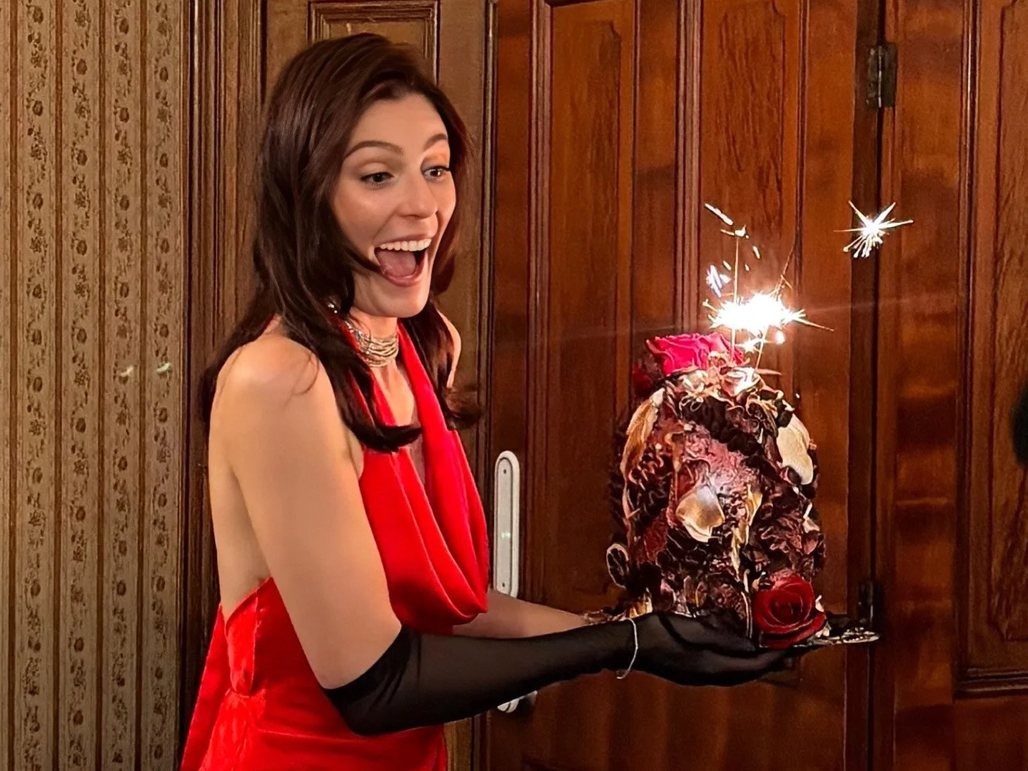 Jane Wills from Shortland Street holding her 30th birthday cake in a red dress