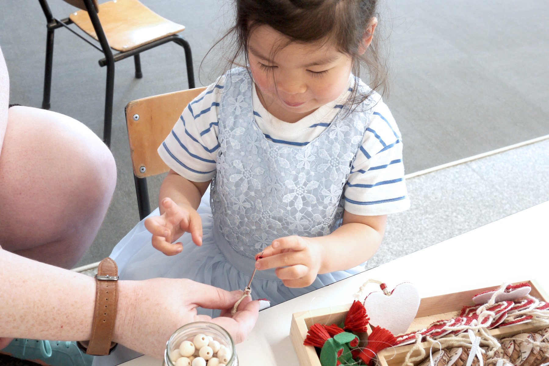Preschool girl making Christmas crafts with a qualified kindy teacher at a Remuera childcare