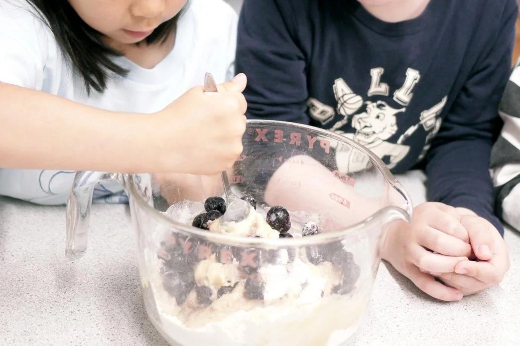 Children baking blueberry muffins together at Remuera kindy