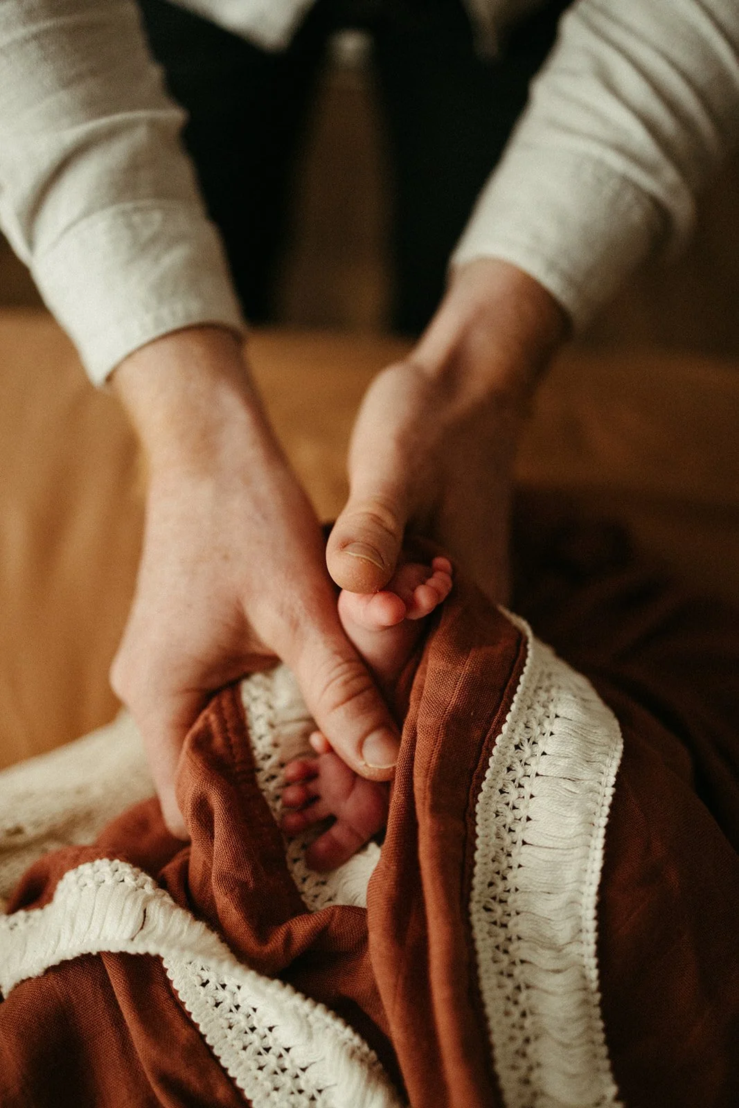 A father's hands cradle newborn tiny feet and are photographed in a beautiful way by Belinda Dorman Photo and Film, a well established Brisbane newborn photographer.