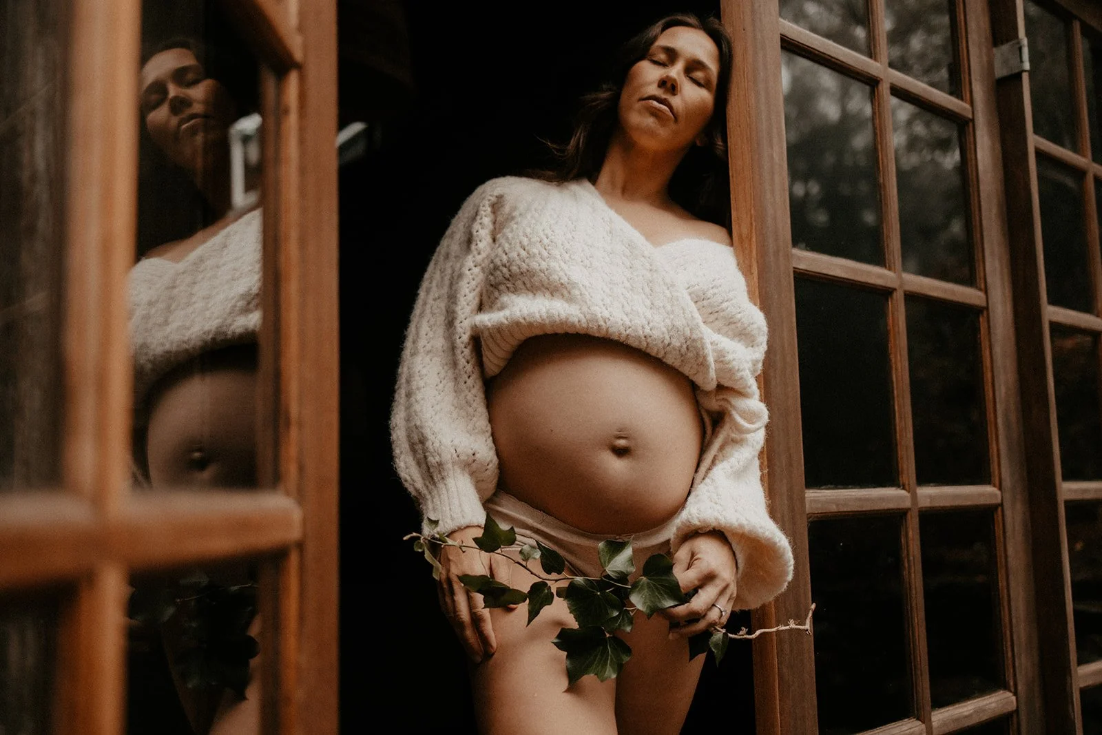 A maternity portraits artistically taken in the doorway framework of stunning Samford photo location Elm Haus, Mount Glorious.