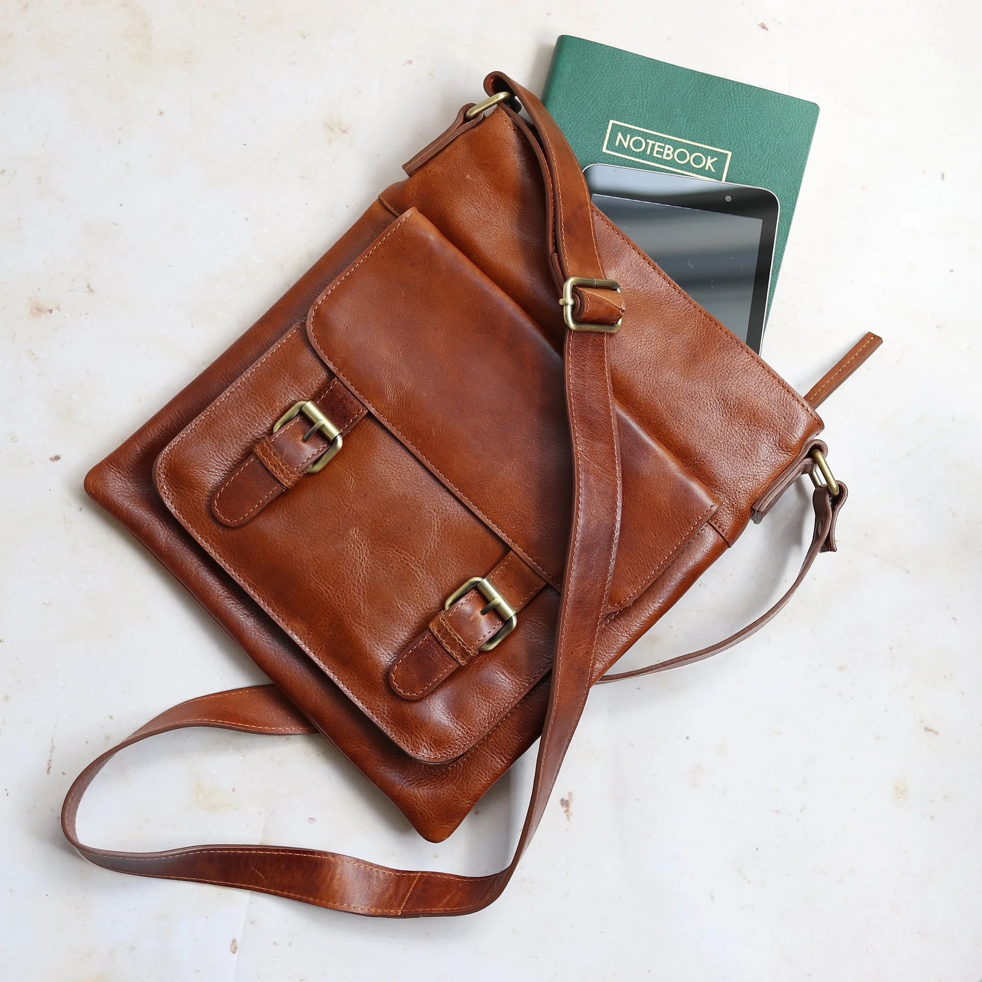 Ashley tan leather crossbody bag shown laying flat with books inside