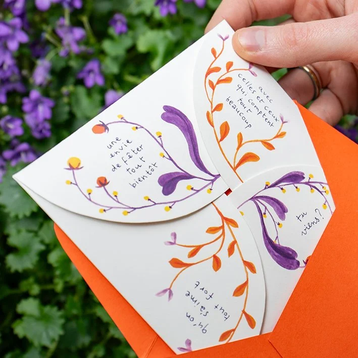 Un faire part de mariage sous forme d'une carte pliée en forme de fleur avec des dessins de branches et de fleurs violettes et orange, contenant des messages poétiques écrits en français.