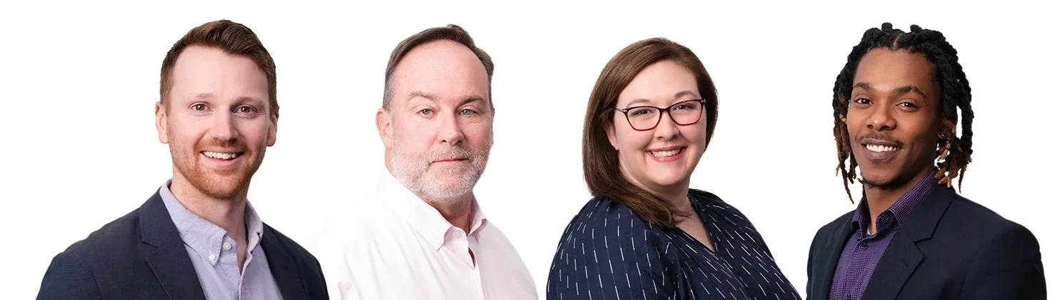 Four diverse adults posing for a professional photo against a white background, smiling and dressed in business casual attire.